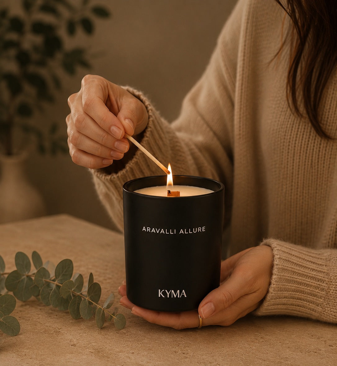 Hands lighting a Kyma soy candle in a matte black vessel